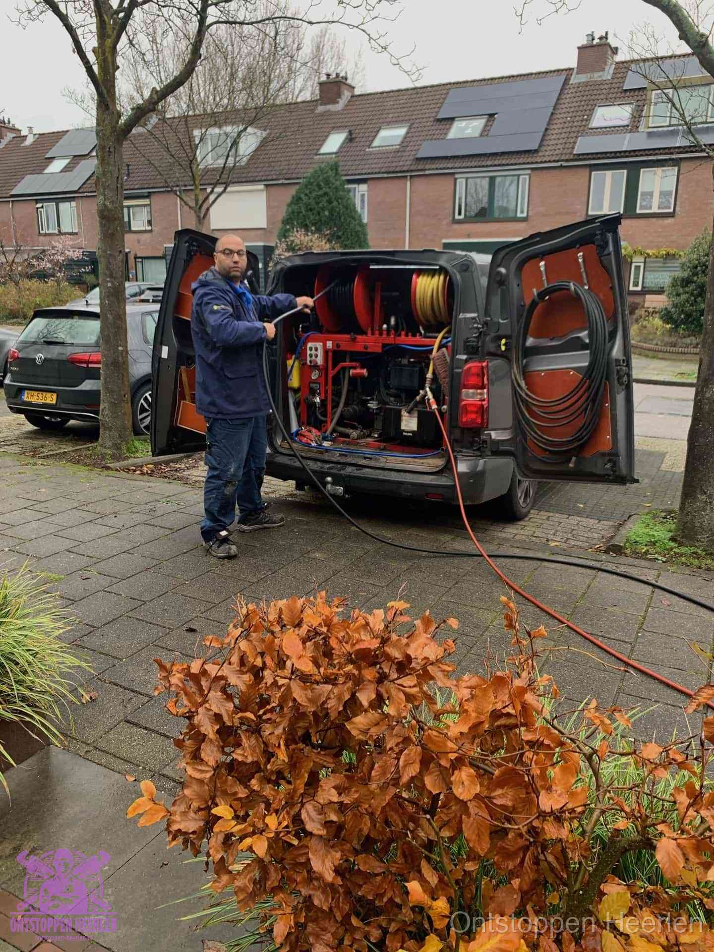 Monteur met rioolreinigingsbus levert rioolservice in de wijk in Heerlen