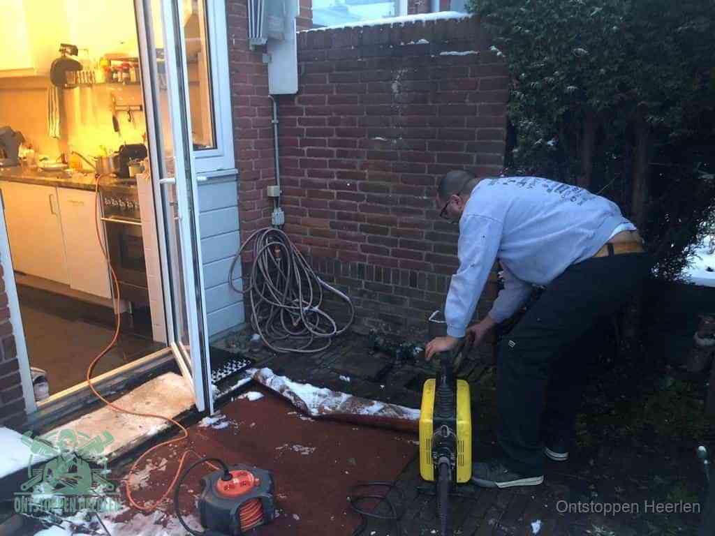 Een monteur werkt buiten bij een open riool-/grondput met een elektrische ontstoppingsmachine om een verborgen afvoerprobleem op te sporen in Heerlen