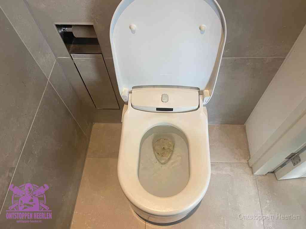 Een wit hangtoilet waarin een prop wc-papier op het water blijft drijven, een duidelijk signaal van een verstopte wc in Heerlen