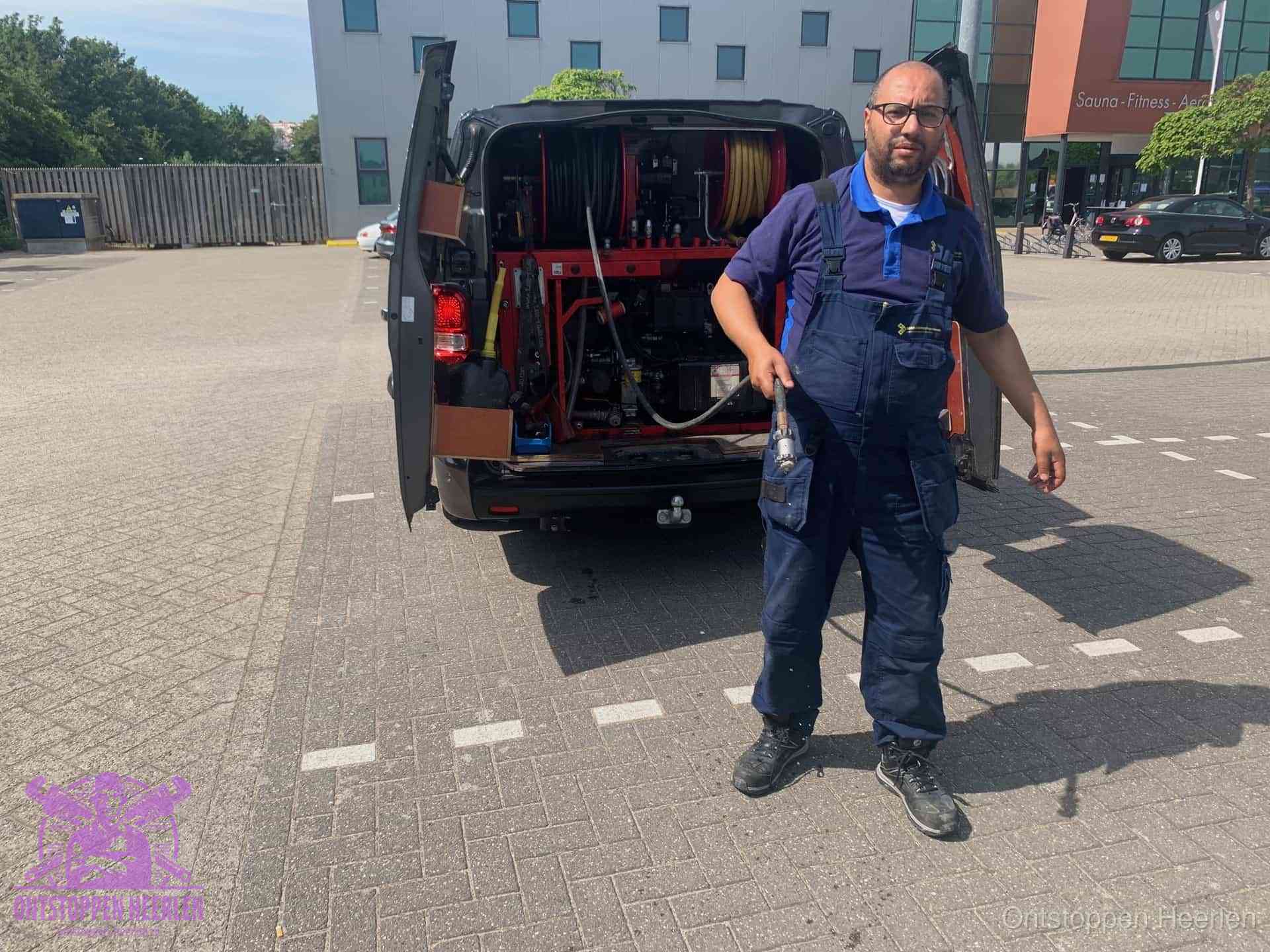 Een monteur bij zijn bestelbus met een hogedruk- en rioolreinigingsunit, klaar om de oorzaak van terugkerende wc-verstoppingen aan te pakken in Heerlen
