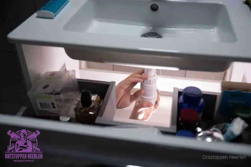Een pompfles met zeep boven een wastafel in de toiletruimte, de warm water en afwasmiddel-methode om de wc te ontstoppen in Heerlen