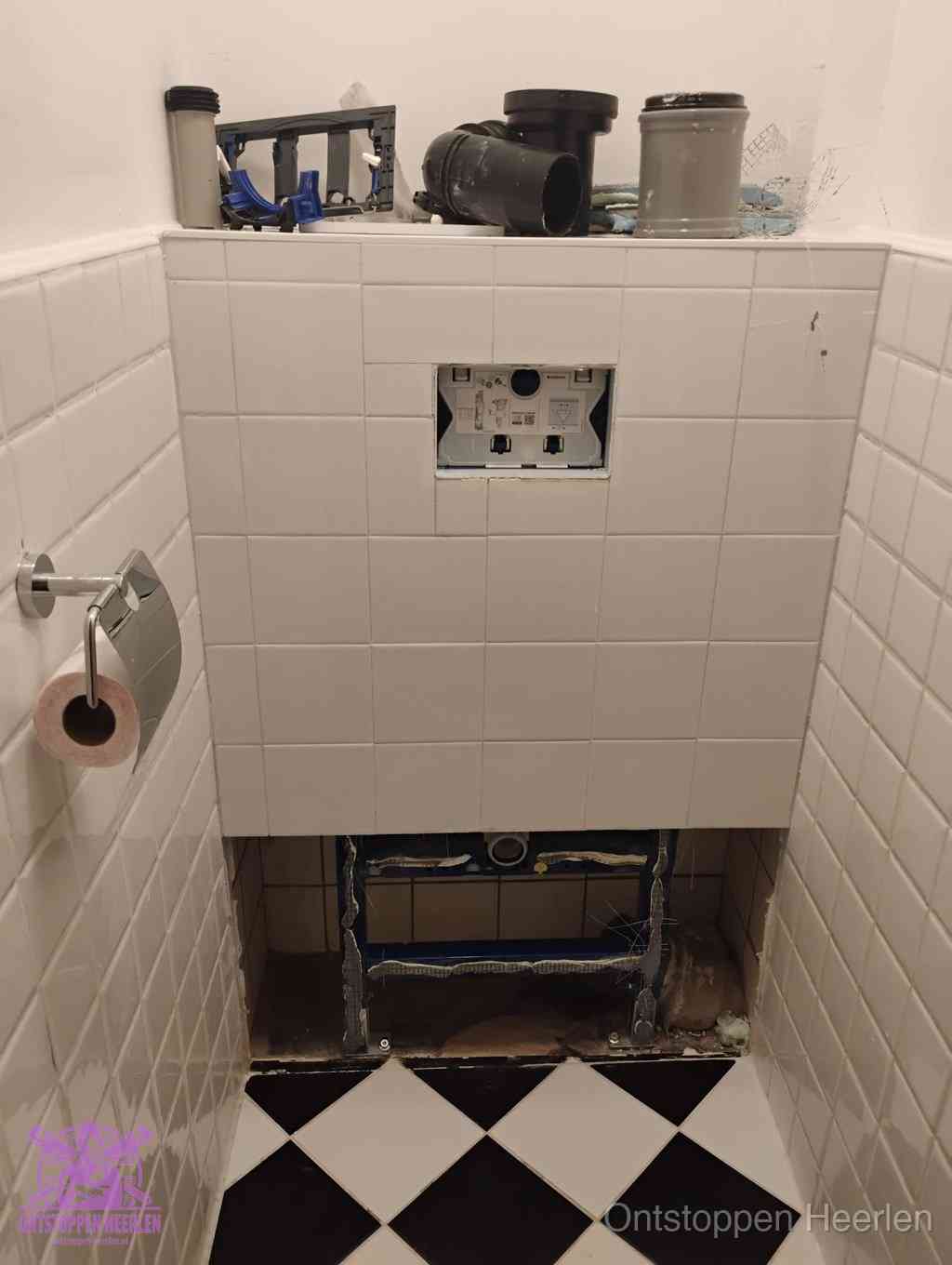 Een toiletruimte waar het hangtoilet en de inbouwreservoir-onderdelen zijn vrijgelegd voor onderhoud, periodiek nazicht voorkomt een wc-verstopping in Heerlen