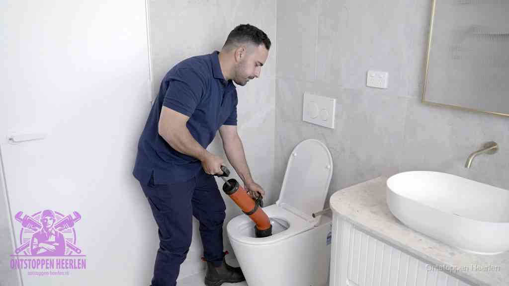 Een monteur gebruikt een handmatige perspomp (toiletontstopper) op een wandcloset tijdens het professioneel wc ontstoppen in Heerlen