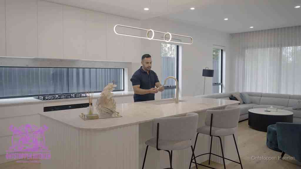Een bewoner bij de keukenspoelbak die zelf aan de slag gaat met een verstopte gootsteen in Heerlen